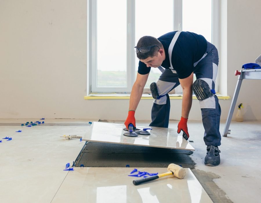 A male construction worker installs a large ceramic tile